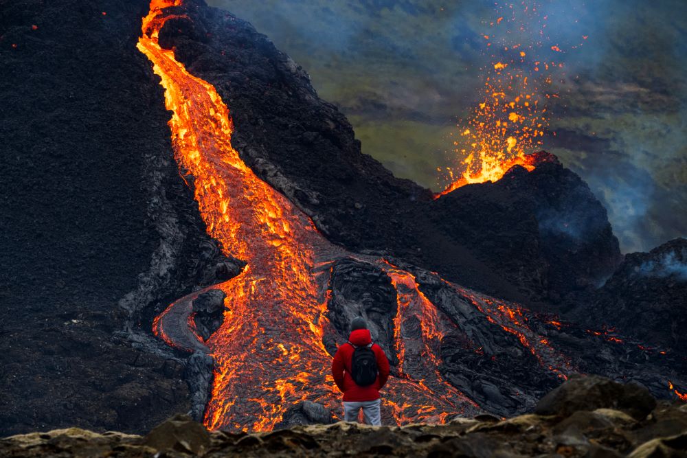 Tourist watching lava flow from the crater in Geldingadalur on the Reykjanes Peninsula