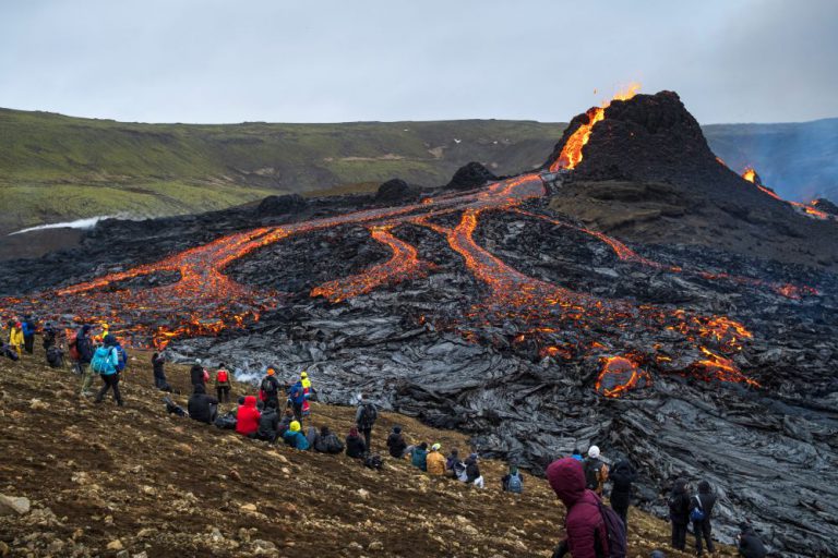 People admiring the Reykjanes peninsula eruption from the edge of the flowing lava