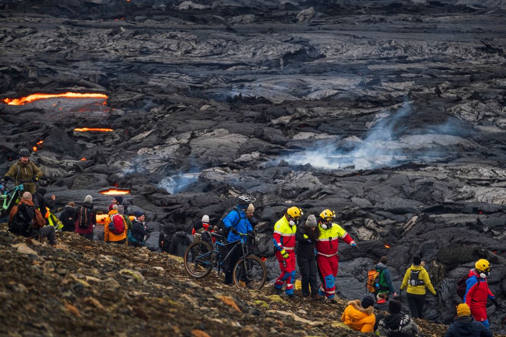 Search-and-rescue volunteers assist a tourist by the new lava in Geldingadalur on the Reykjanes Peninsula
