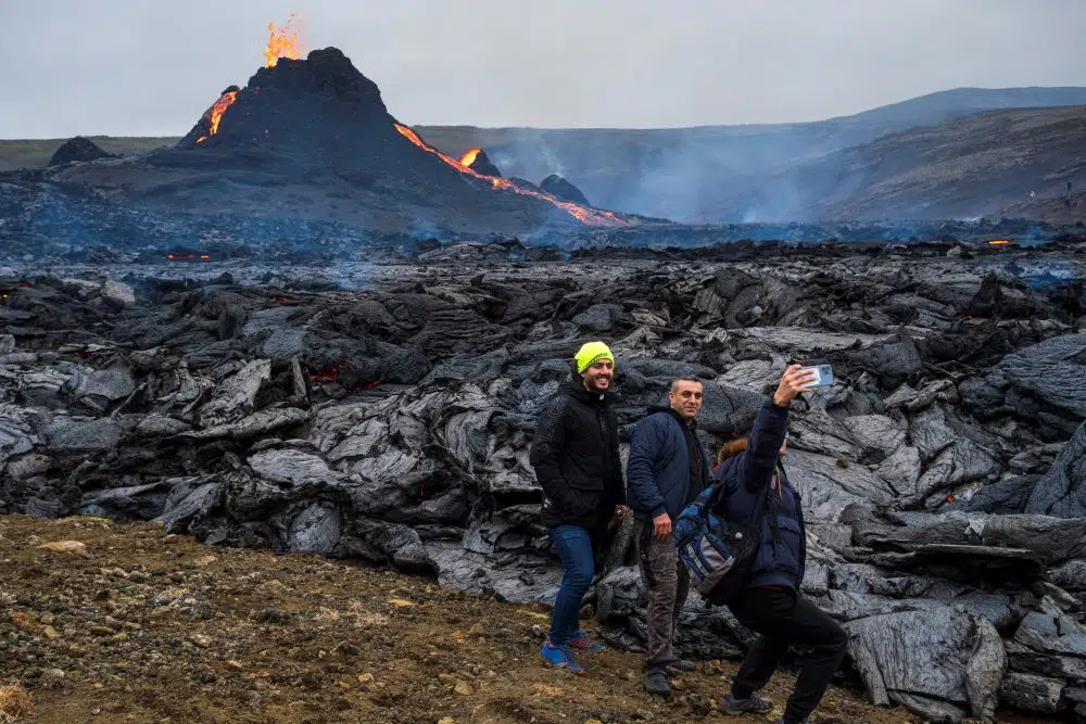Tourists catch a selfie by the edge of the new lava flowing from the crater in Geldingadalur on the Reykjanes peninsula