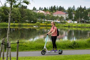 A person riding an electric scooter by the Reykjavík city centre pond.
